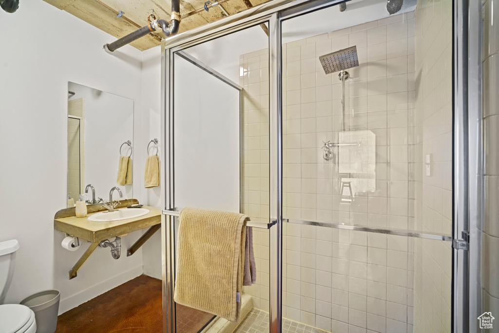 Bathroom featuring an enclosed shower, toilet, and sink