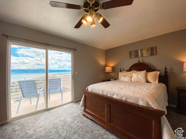 Bedroom with light carpet, ceiling fan, access to exterior, and a water view