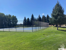 View of tennis court with a yard
