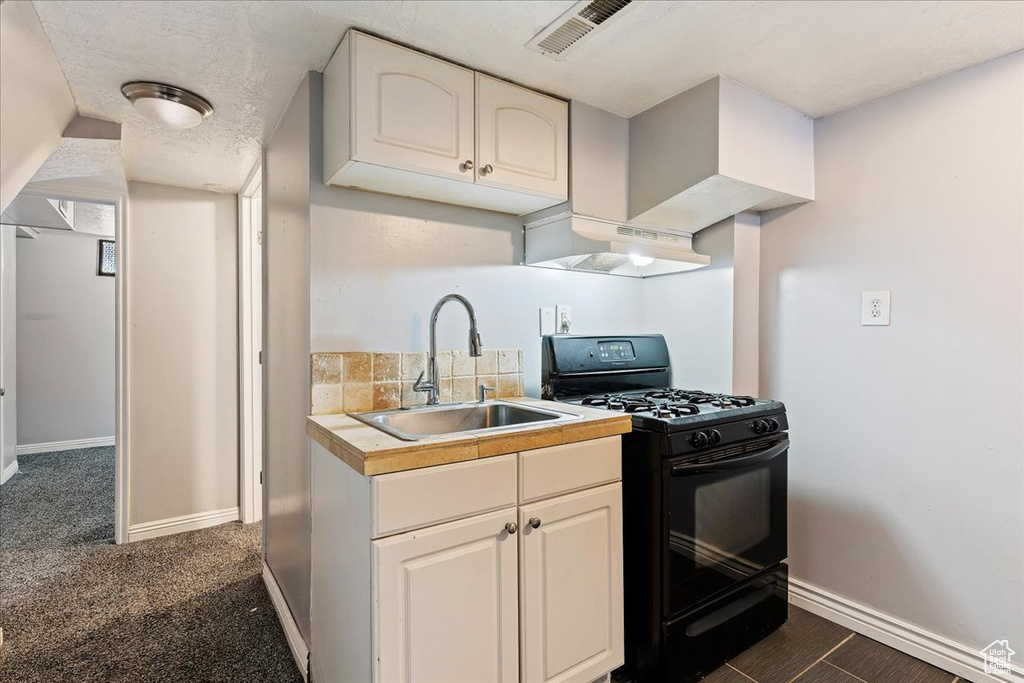 Kitchen featuring dark carpet, premium range hood, black range with gas cooktop, and sink