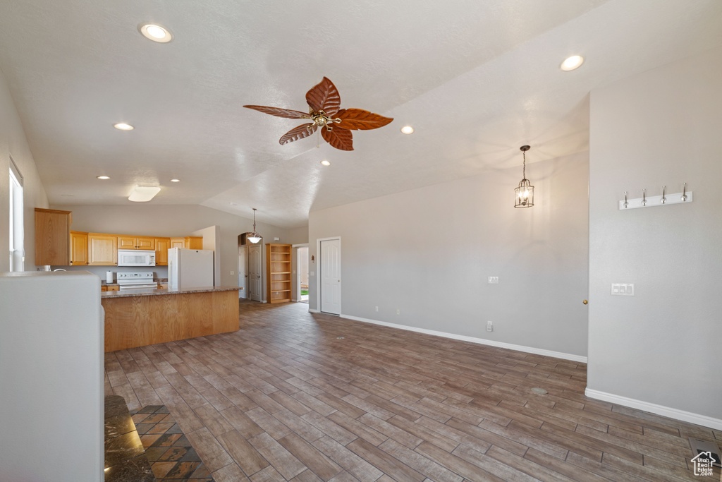 Unfurnished living room featuring hardwood / wood-style floors, lofted ceiling, and ceiling fan