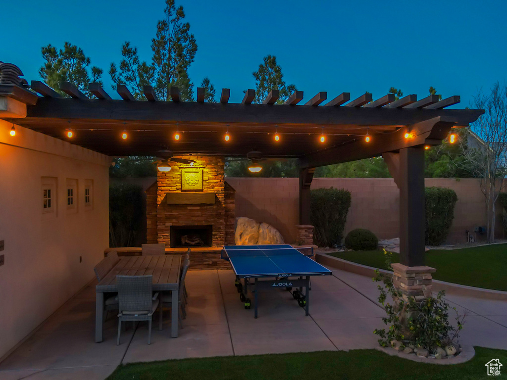 Patio terrace at night featuring an outdoor stone fireplace
