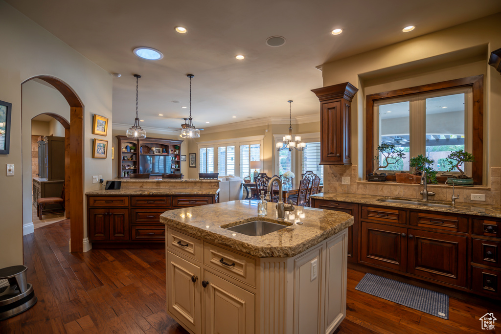 Kitchen featuring a kitchen island with sink, an inviting chandelier, sink, tasteful backsplash, and dark hardwood / wood-style flooring