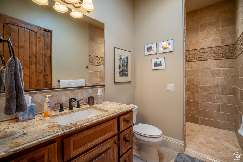 Bathroom featuring backsplash, a tile shower, tile floors, toilet, and oversized vanity