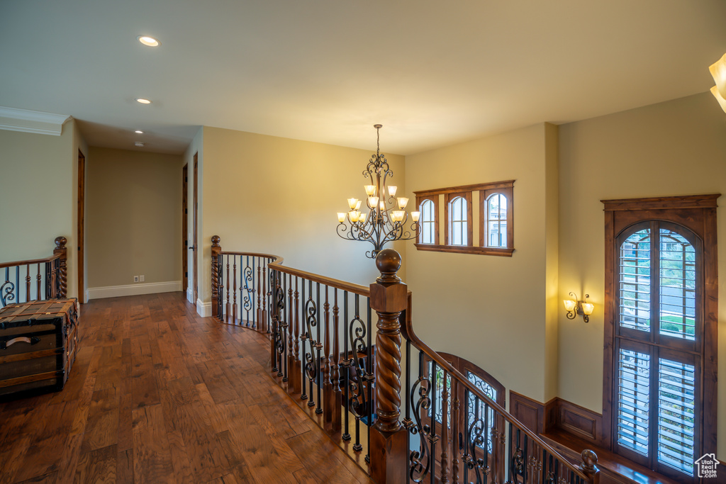 Corridor featuring an inviting chandelier, dark hardwood / wood-style flooring, and crown molding