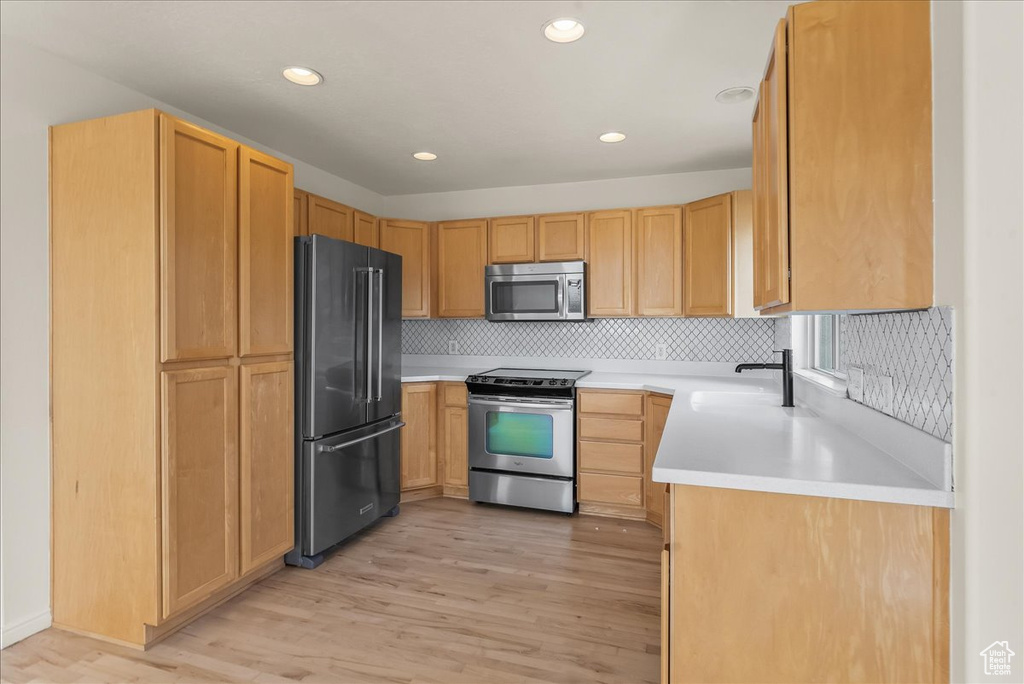 Kitchen featuring sink, light hardwood / wood-style floors, light brown cabinets, backsplash, and appliances with stainless steel finishes