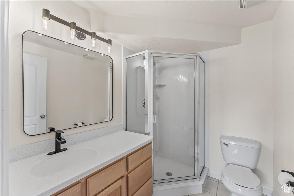 Bathroom featuring an enclosed shower, tile floors, large vanity, and toilet