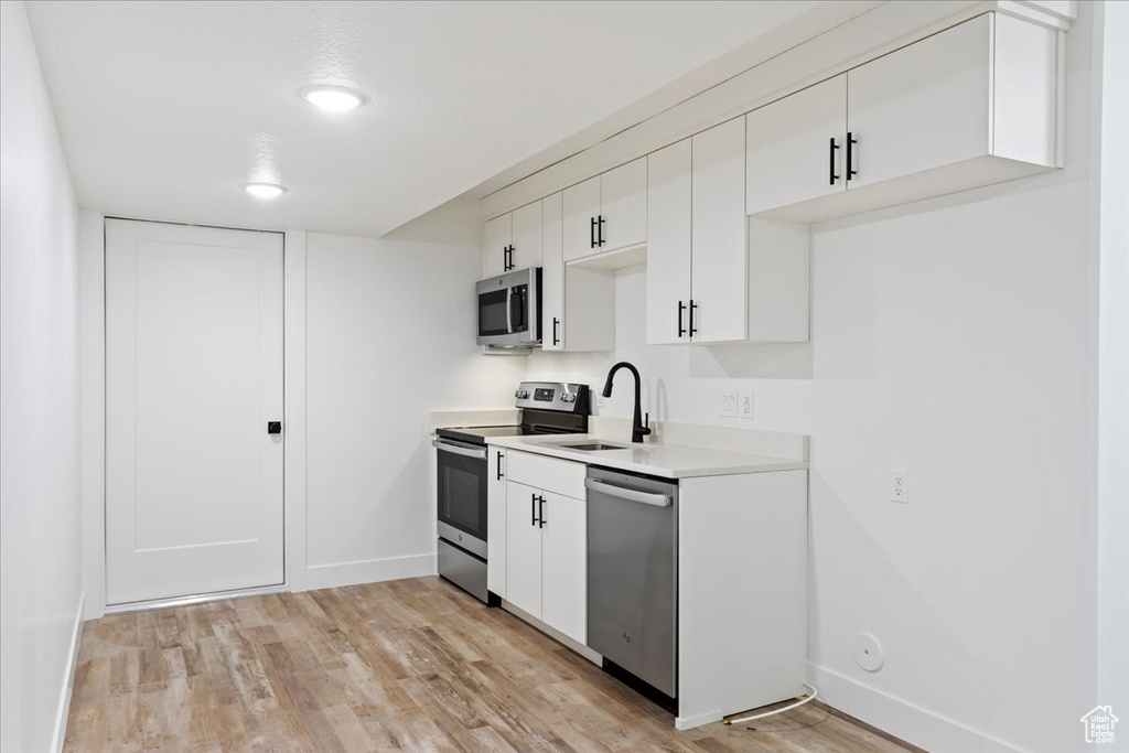 Kitchen featuring white cabinets, stainless steel appliances, light hardwood / wood-style flooring, and sink
