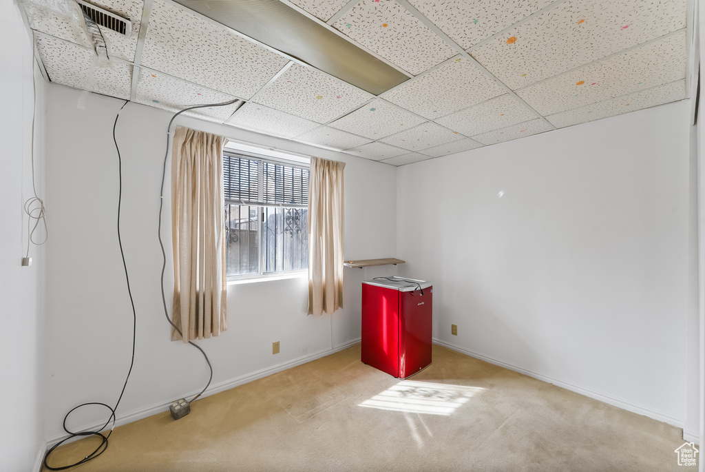 Empty room featuring a drop ceiling and light carpet