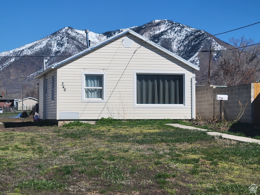 Back of property with a mountain view and a yard