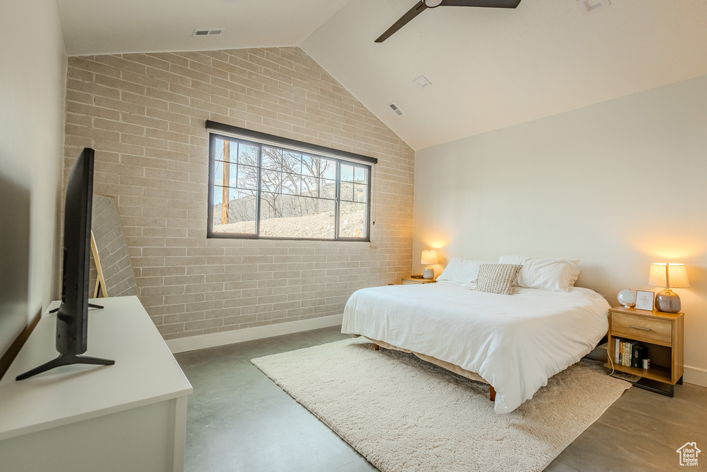 Bedroom with ceiling fan, lofted ceiling, and brick wall