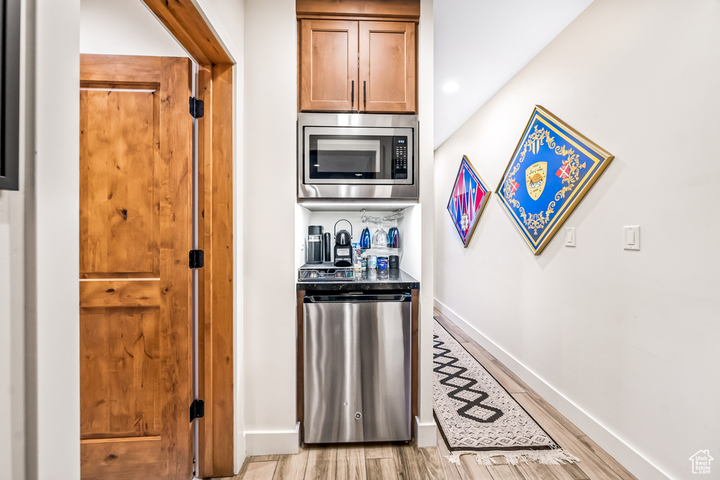Interior space with stainless steel microwave, fridge, and light hardwood / wood-style floors