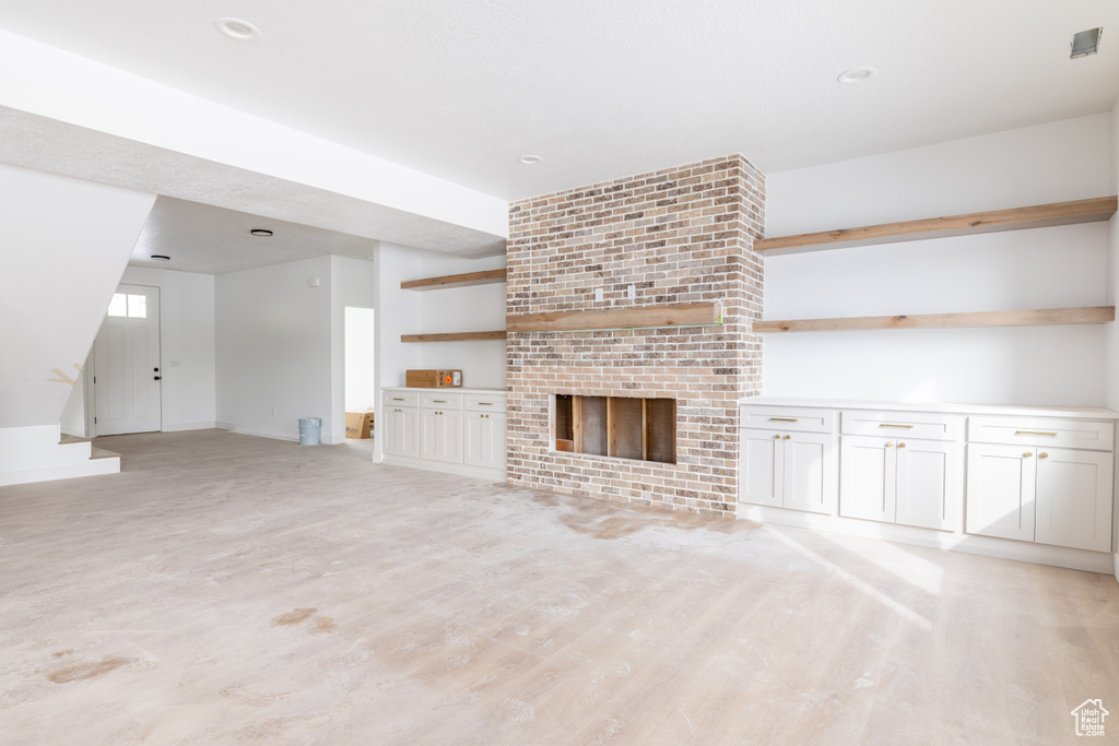 Unfurnished living room featuring a brick fireplace and brick wall