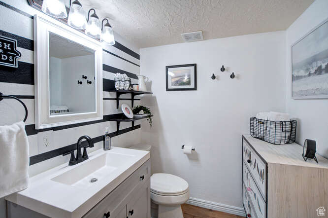 Bathroom featuring hardwood / wood-style flooring, vanity, a textured ceiling, and toilet