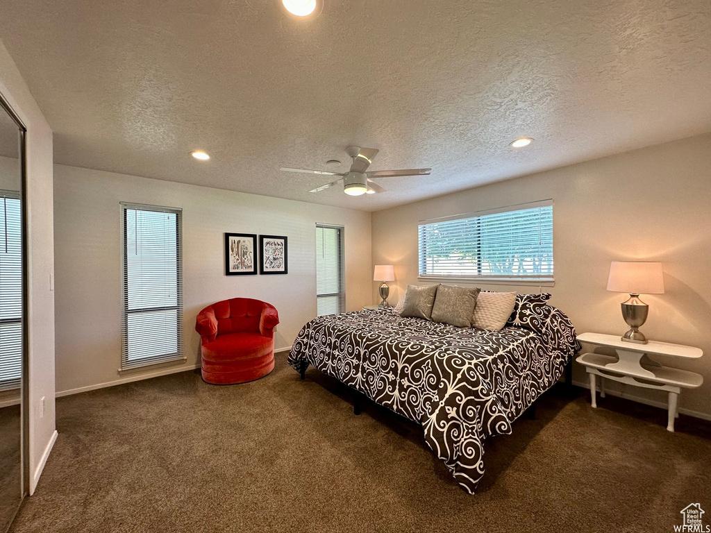 Bedroom with dark carpet, a textured ceiling, and ceiling fan