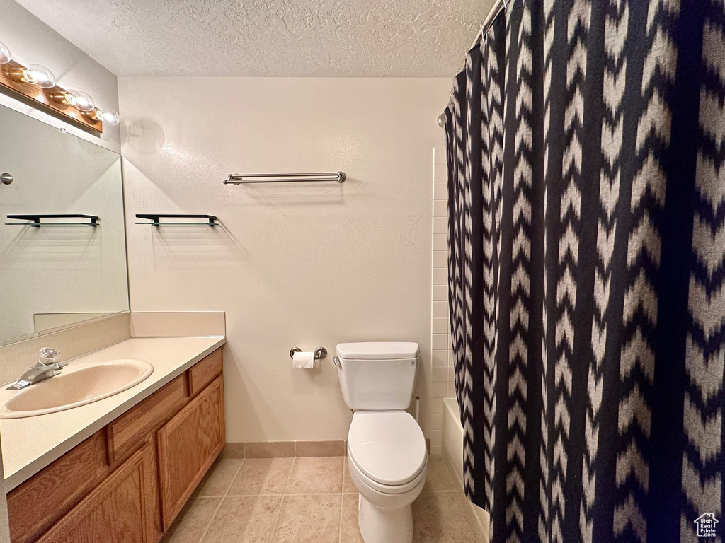 Bathroom featuring tile floors, large vanity, toilet, and a textured ceiling