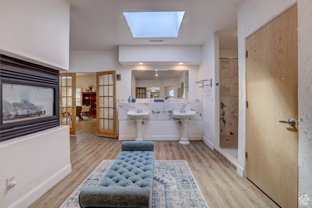 Bathroom with french doors, walk in shower, a skylight, and wood-type flooring