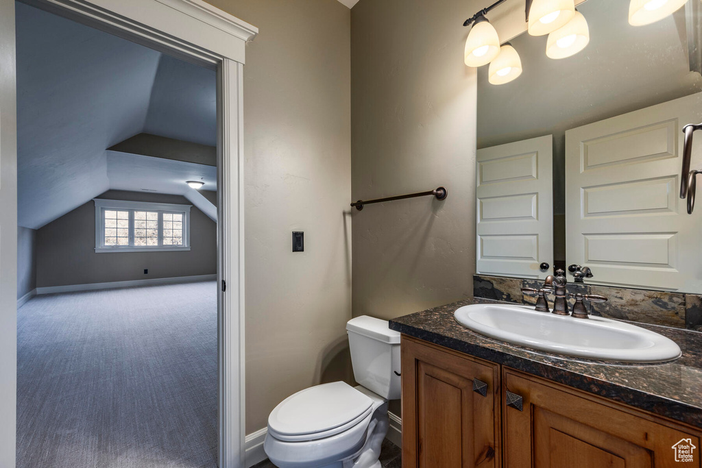 Bathroom featuring vaulted ceiling, toilet, and vanity with extensive cabinet space