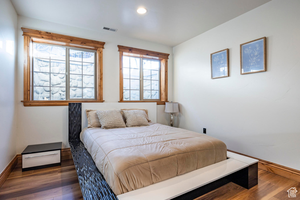Bedroom with multiple windows and dark hardwood / wood-style floors