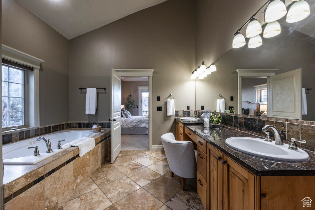 Bathroom featuring plenty of natural light, tile flooring, vaulted ceiling, and large vanity