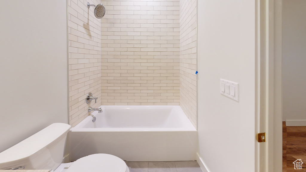 Bathroom featuring wood-type flooring, tiled shower / bath combo, and toilet