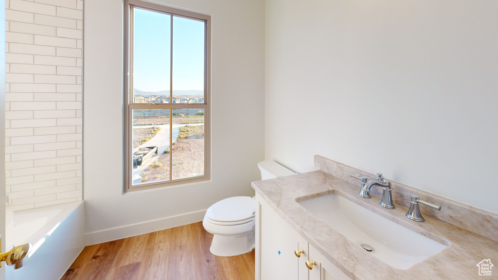 Full bathroom with hardwood / wood-style floors, vanity, toilet, and tiled shower / bath combo