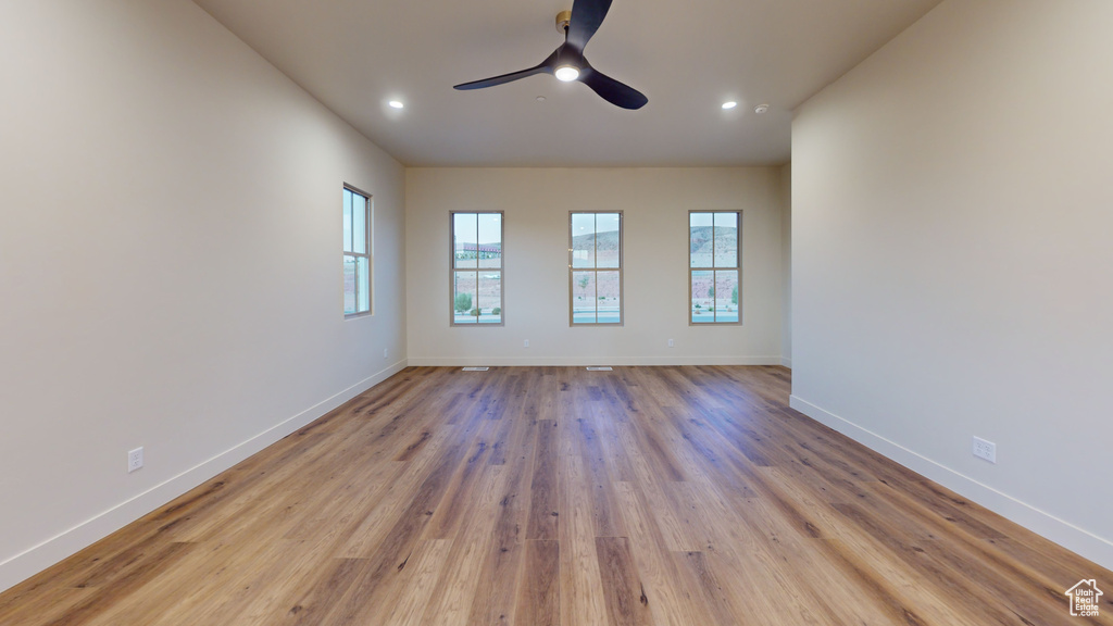 Empty room with ceiling fan and light hardwood / wood-style floors