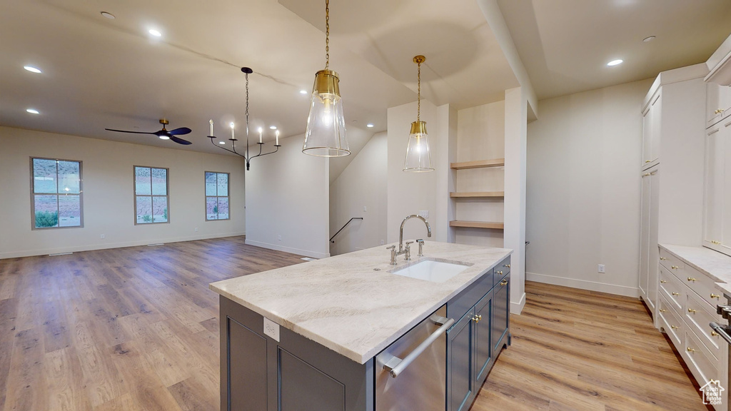 Kitchen featuring white cabinets, light wood-type flooring, hanging light fixtures, and sink