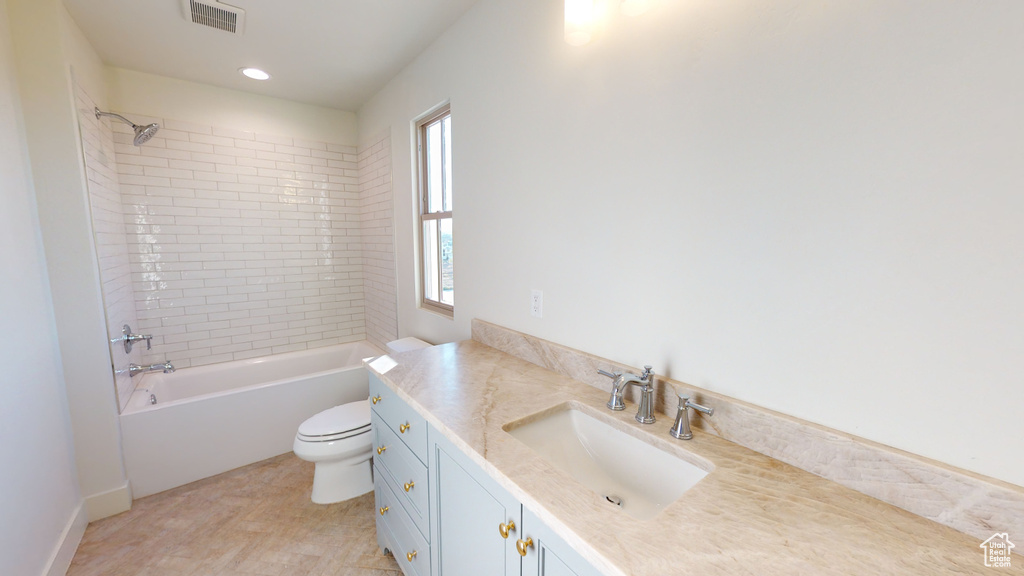 Full bathroom with tiled shower / bath, vanity, and toilet