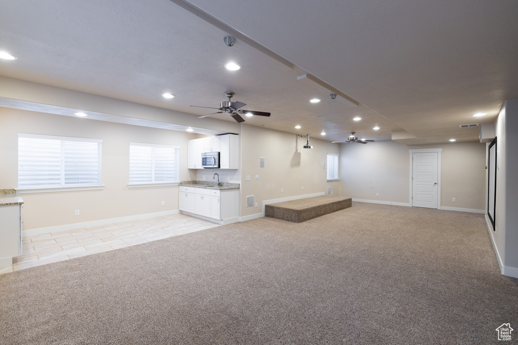 Interior space featuring light carpet, sink, and ceiling fan