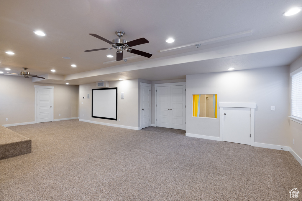 Basement featuring light carpet and ceiling fan