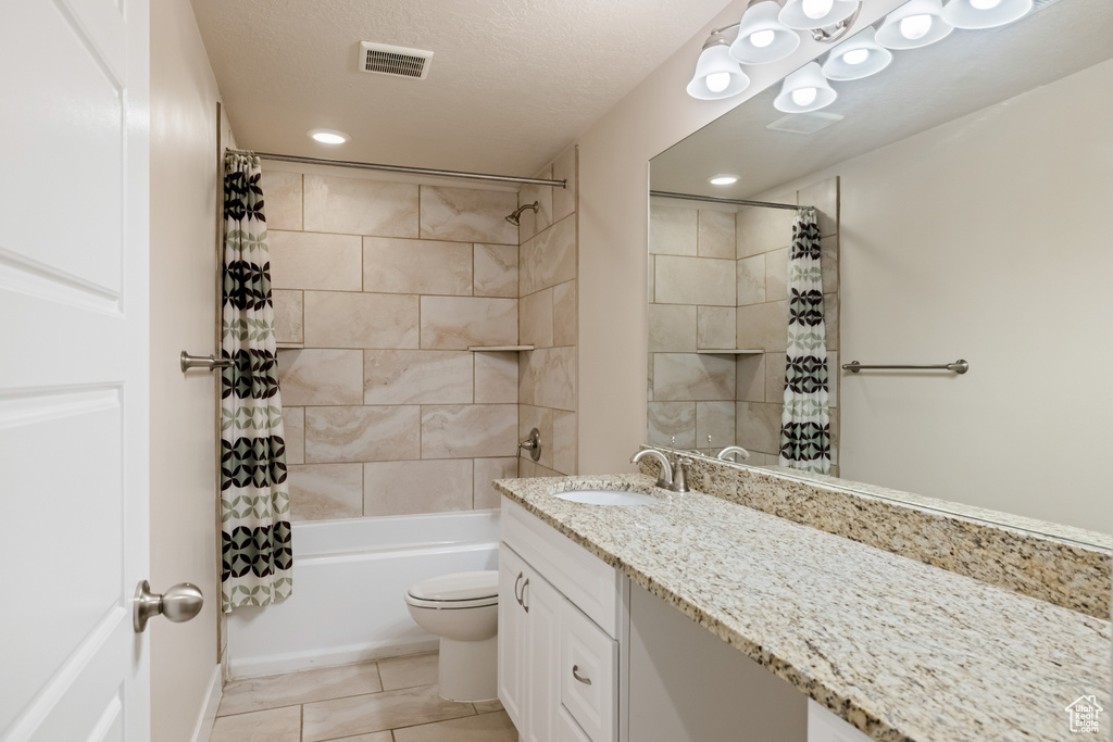 Full bathroom featuring shower / tub combo with curtain, tile flooring, vanity with extensive cabinet space, a textured ceiling, and toilet