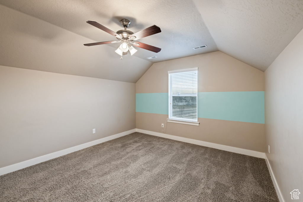 Bonus room featuring vaulted ceiling, a textured ceiling, carpet, and ceiling fan