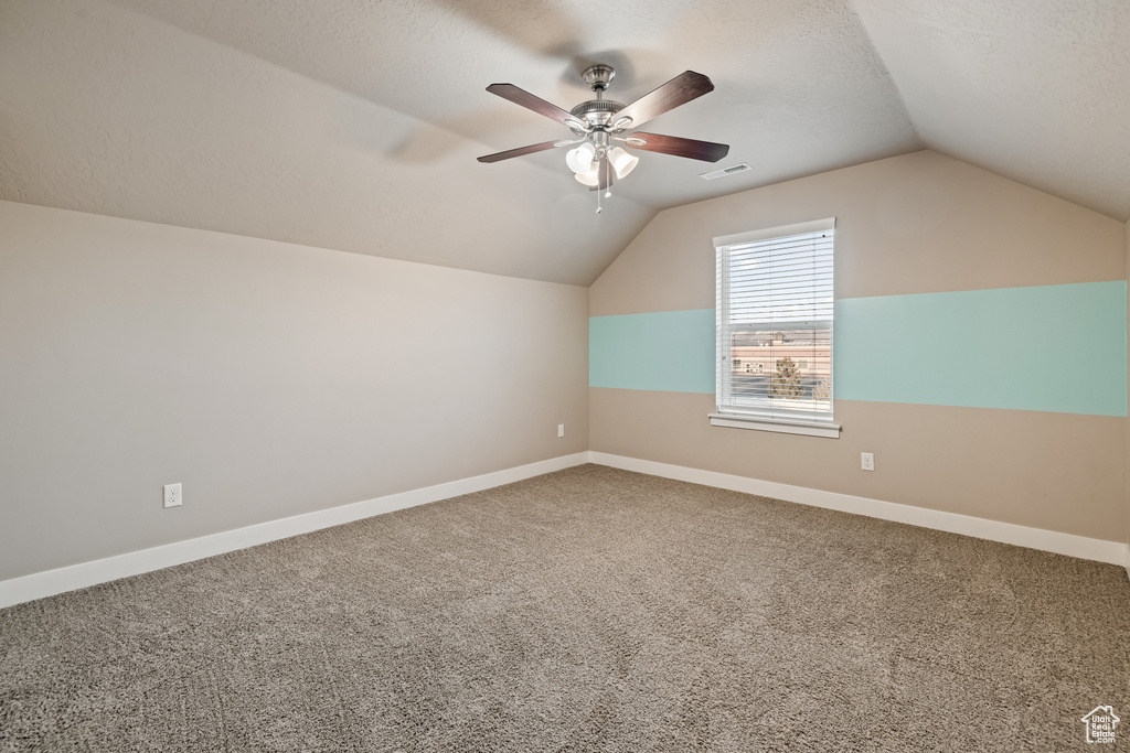 Additional living space with a textured ceiling, lofted ceiling, carpet flooring, and ceiling fan