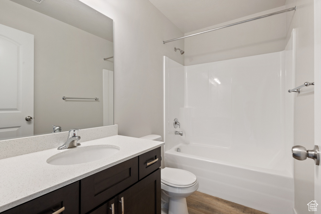 Full bathroom with vanity, shower / washtub combination, toilet, and hardwood / wood-style flooring