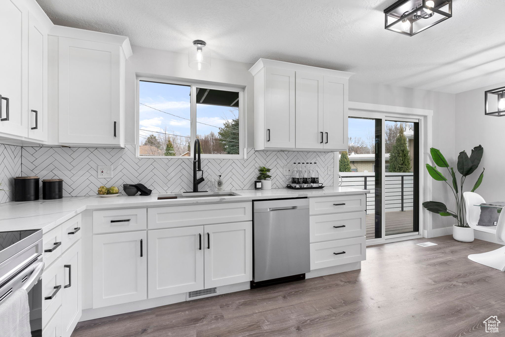 Kitchen featuring dishwasher, sink, tasteful backsplash, and white cabinetry