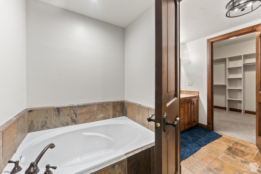 Bathroom with tile floors, vanity, and tiled bath