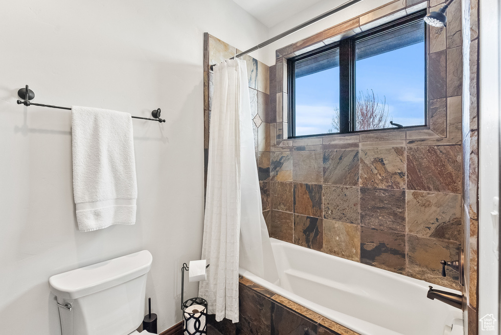 Bathroom featuring toilet and shower / bath combo with shower curtain