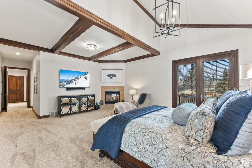 Carpeted bedroom with an inviting chandelier, beam ceiling, access to outside, and a tile fireplace