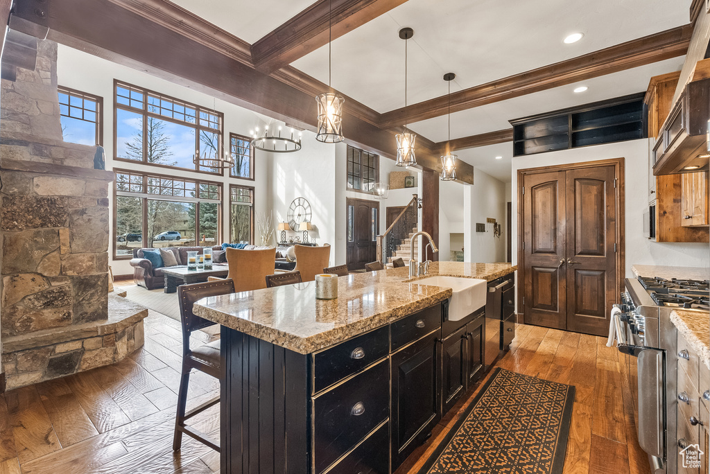 Kitchen with a kitchen island with sink, stainless steel appliances, a chandelier, dark hardwood / wood-style floors, and a kitchen bar
