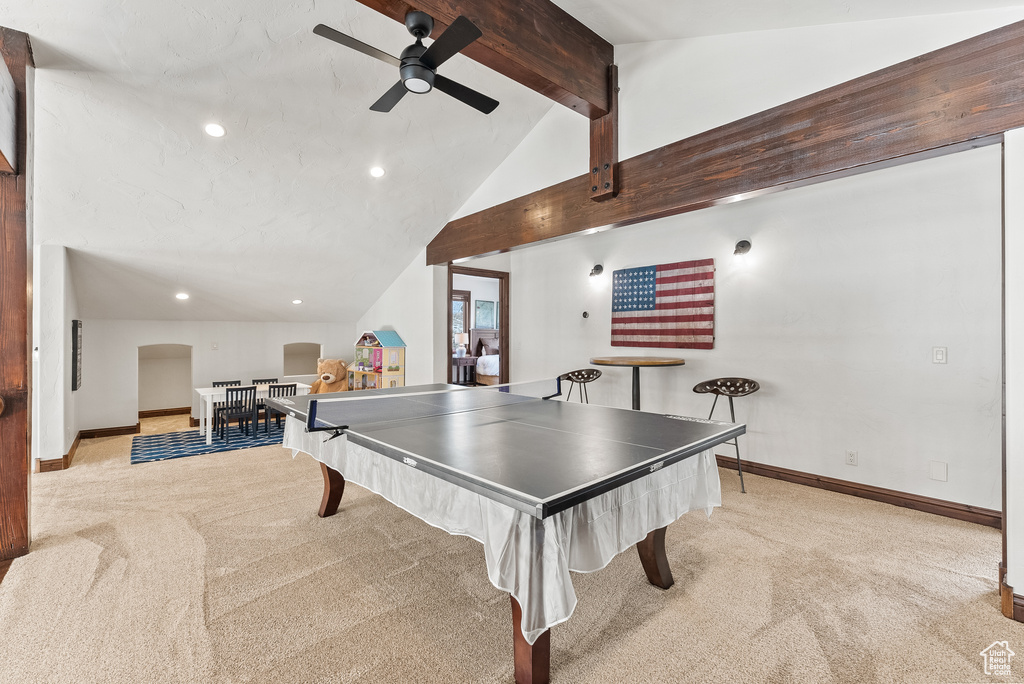 Recreation room featuring light colored carpet, high vaulted ceiling, ceiling fan, and beamed ceiling