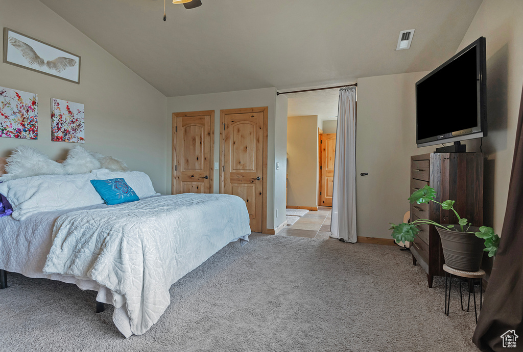 Bedroom featuring light colored carpet, lofted ceiling, and ceiling fan