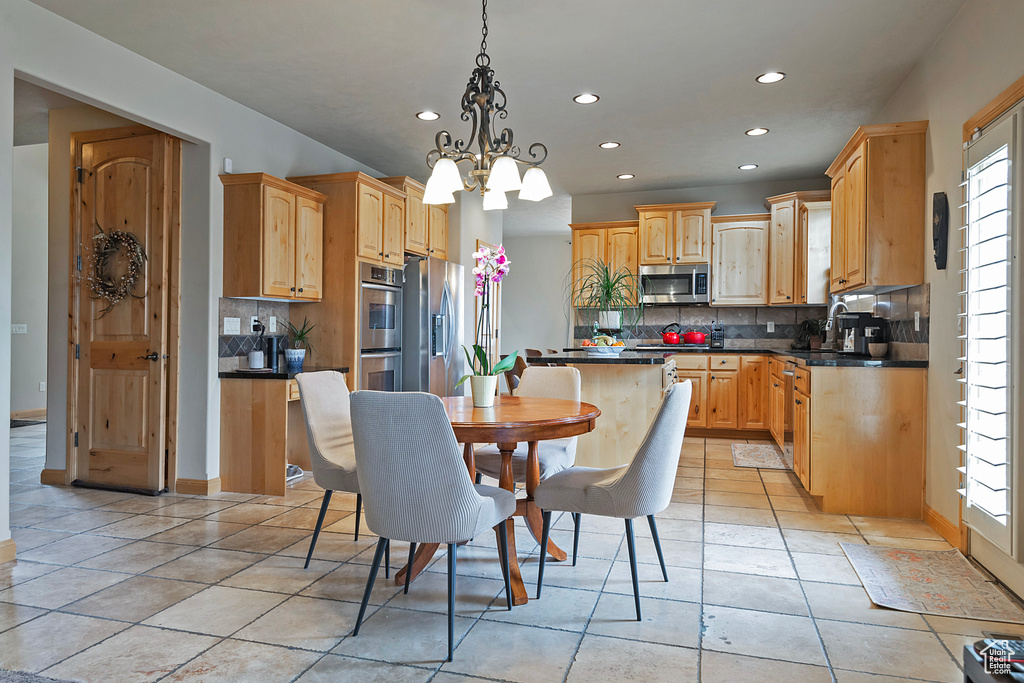 Kitchen featuring a notable chandelier, tasteful backsplash, stainless steel appliances, and a healthy amount of sunlight