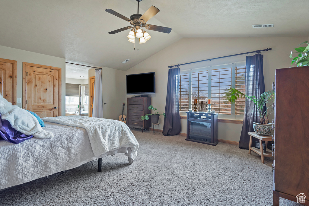 Bedroom featuring multiple windows, lofted ceiling, light colored carpet, and ceiling fan