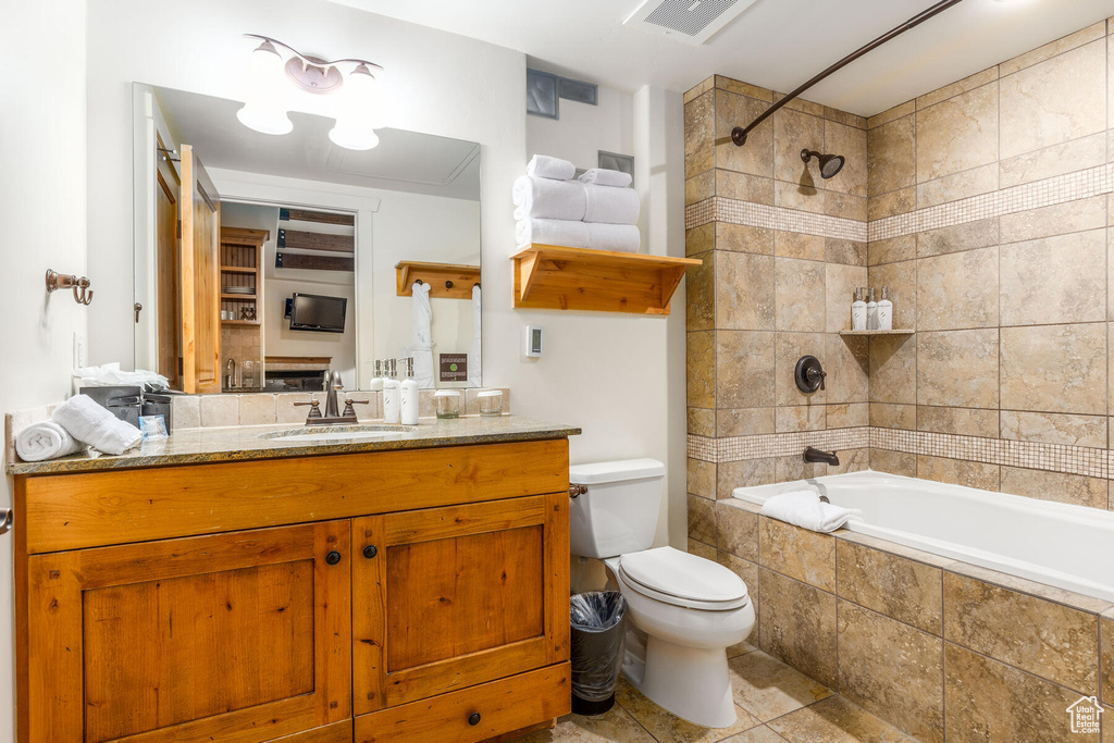 Full bathroom featuring tiled shower / bath combo, vanity, toilet, and tile flooring