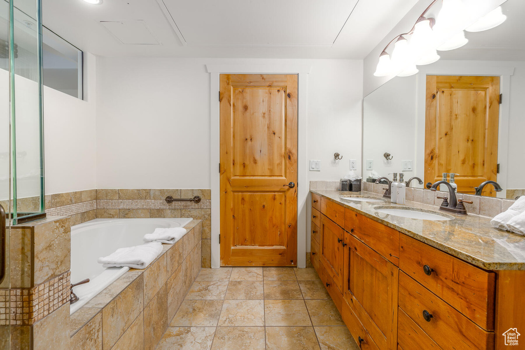 Bathroom featuring vanity, a relaxing tiled bath, and tile floors