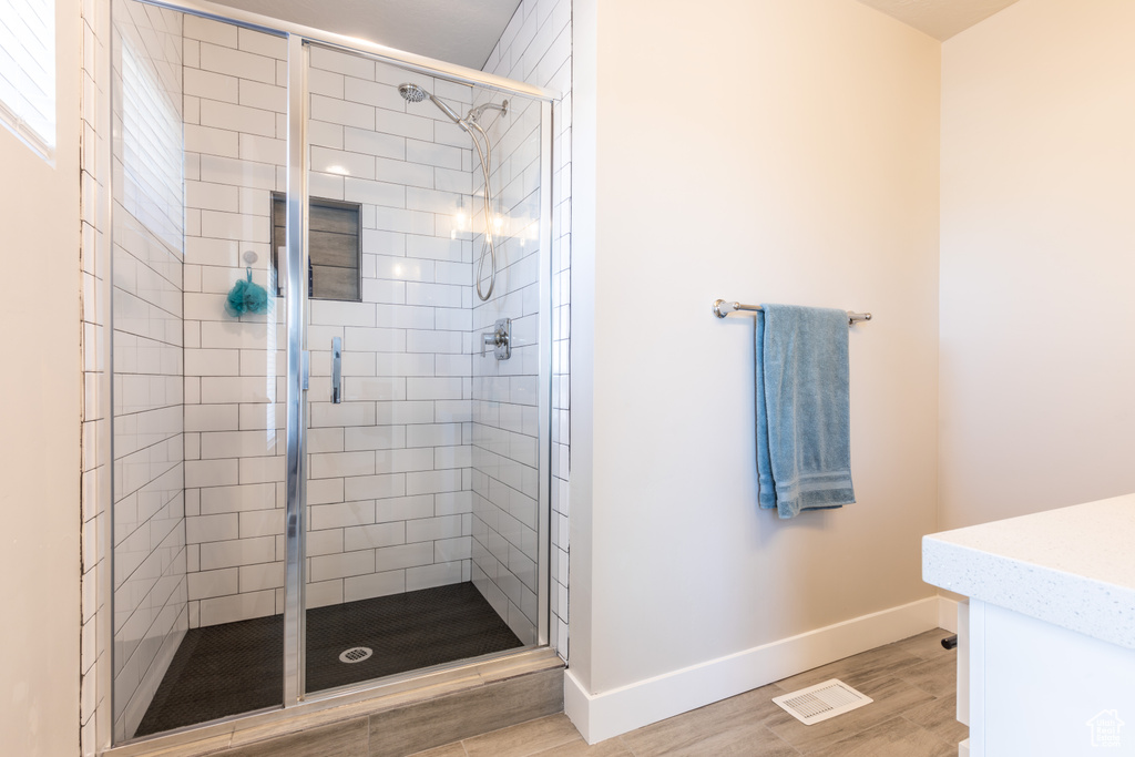 Bathroom featuring hardwood / wood-style floors and a shower with shower door