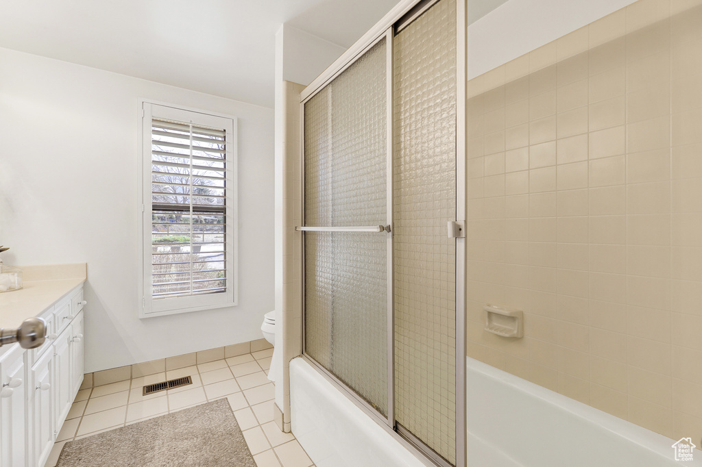 Full bathroom with toilet, tile floors, shower / bath combination with glass door, and vanity