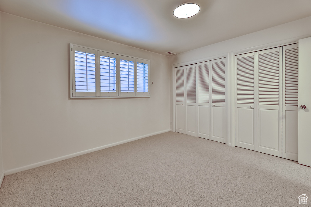 Unfurnished bedroom with two closets and light carpet