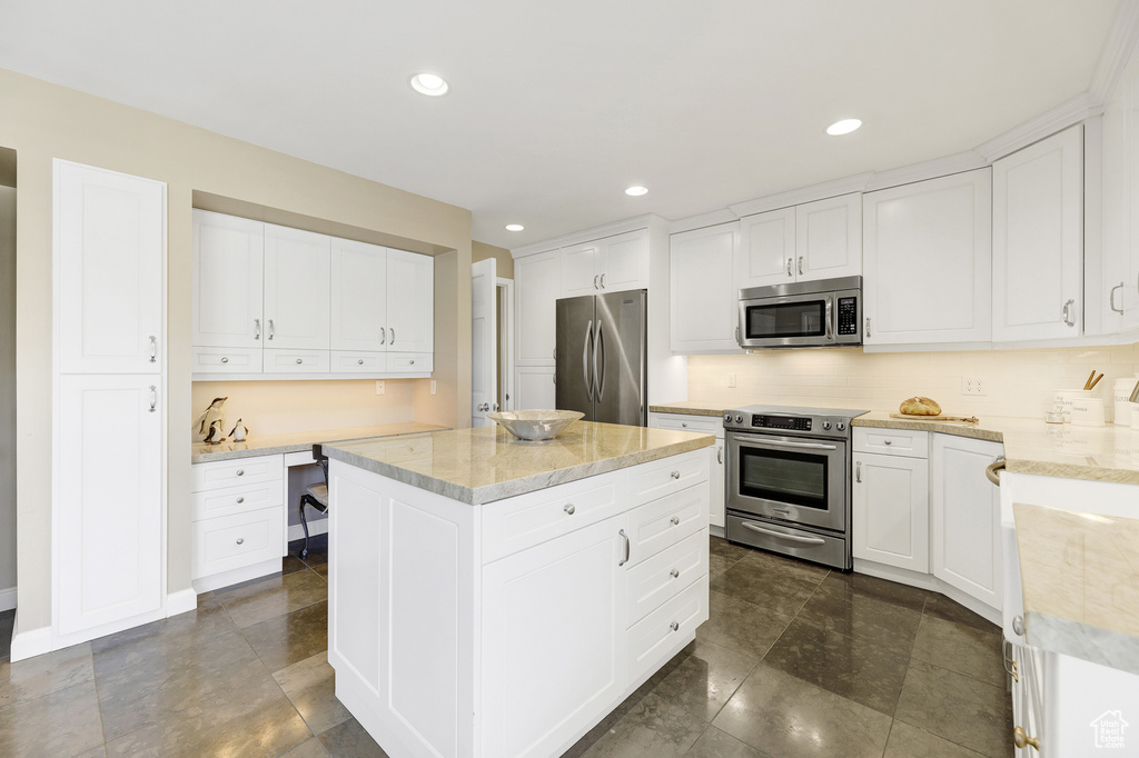 Kitchen with a kitchen island, appliances with stainless steel finishes, and white cabinetry